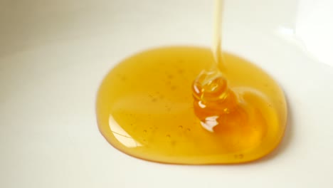 pouring honey: close-up macro shot of golden honey dripping onto a white surface