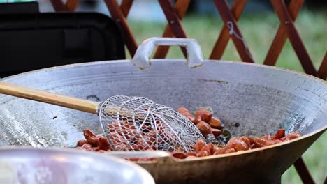 cooking sausages in a large outdoor pan