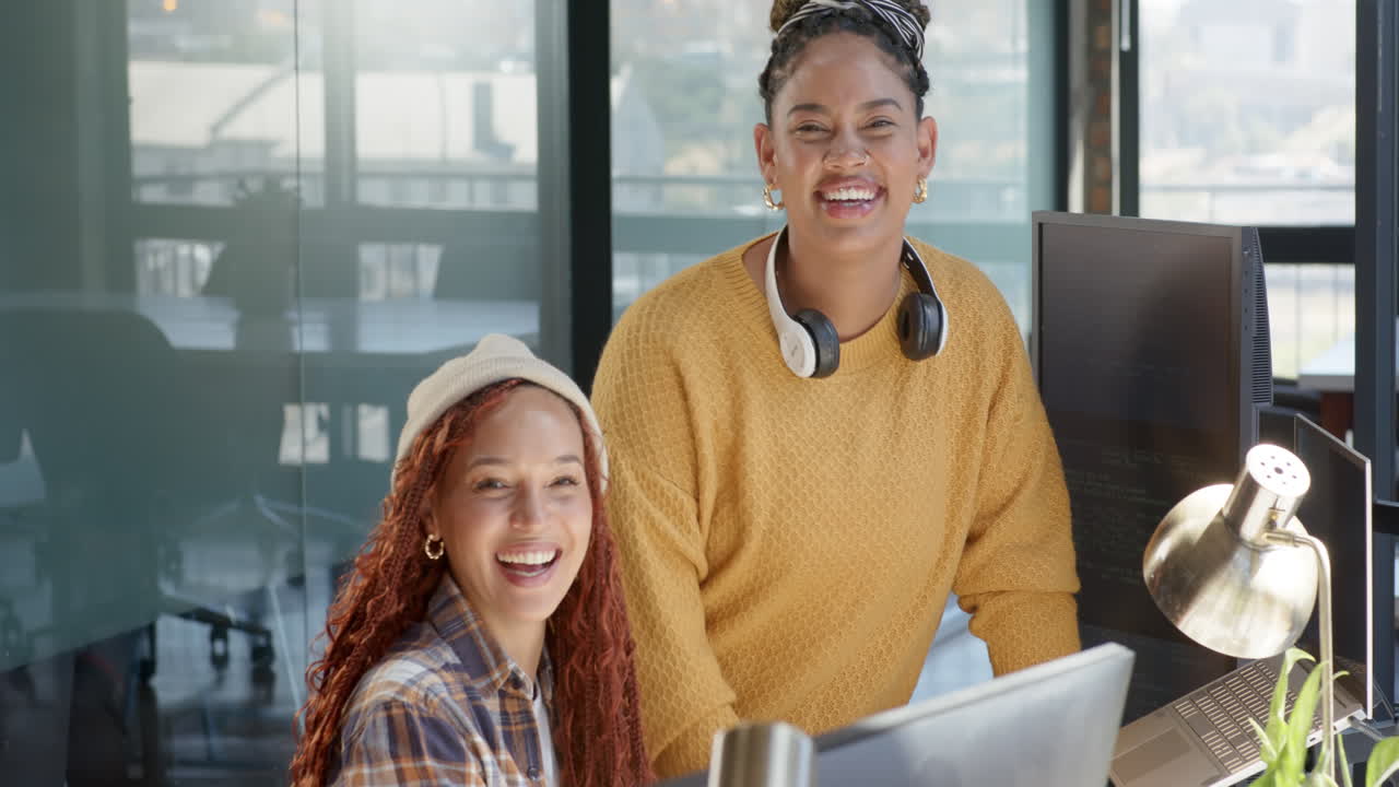 Collaborating on coding project, diverse female team using computers and headphones in office