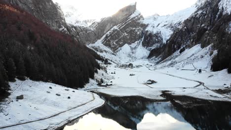 sobrevuelo aéreo a través de seealpsee en appenzell, suiza en invierno con nieve y un reflejo de los picos alpstein en el lago - 4k