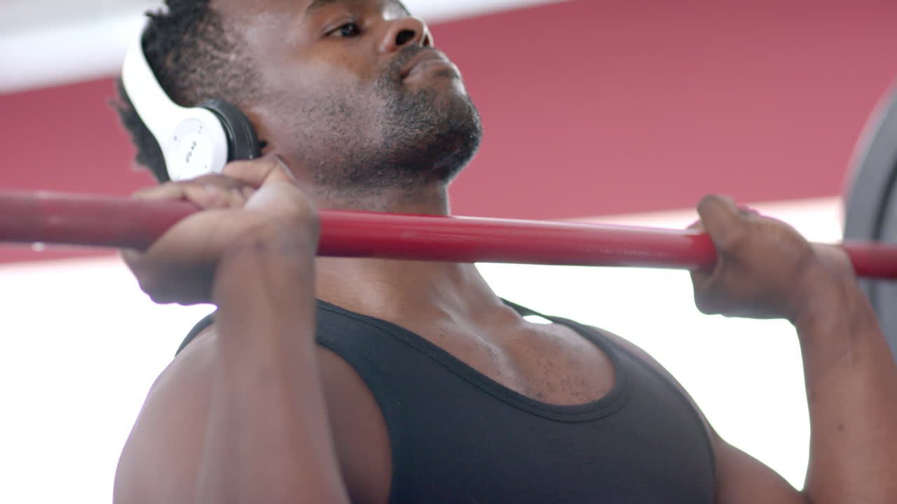 Fit African American man exercising at the gym and lifting weights