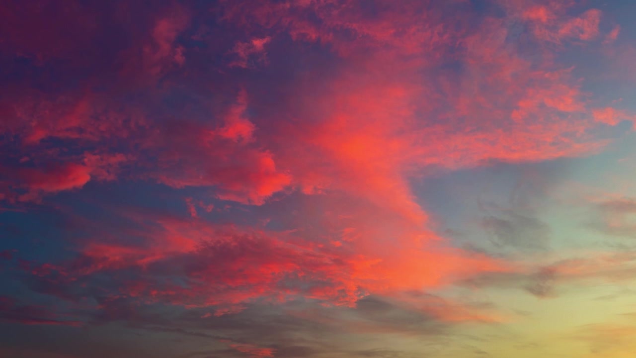 Um brilho dramático do pôr do sol ilumina o céu e as nuvens com a luz quente do entardecer. Tomada estática.