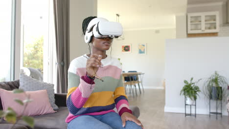 african american young woman wearing virtual reality headset, sitting on couch at home, at home, cop