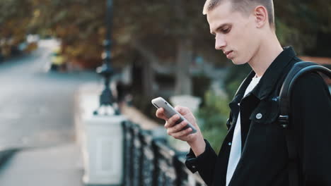 young student using mobile phone outdoors.