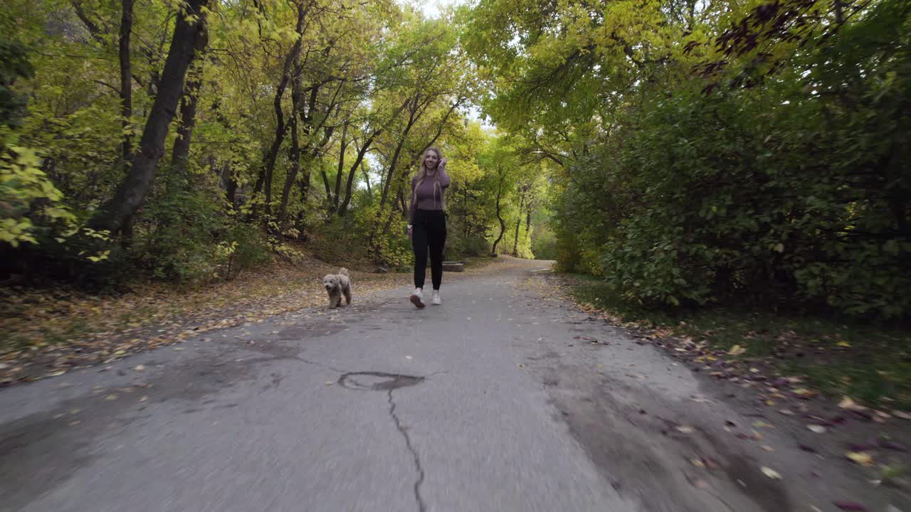mujer y perro mascota caminando por un sendero al aire libre en el bosque de montaña - tiro de muñeca
