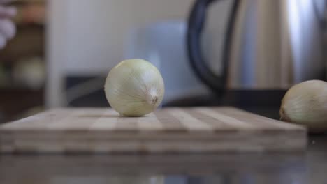 static shot of a man placing onions ona wooden chopping board