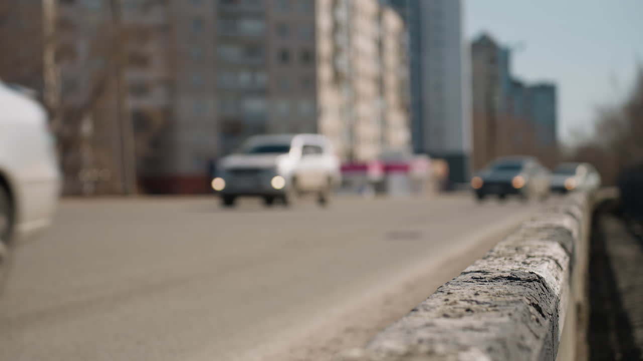 배경에 움직이는 자동차와 함께 도시 도로의 가까운 시각, 초점은 날씨의 도로 장벽과 움직이는 자동차에 있습니다