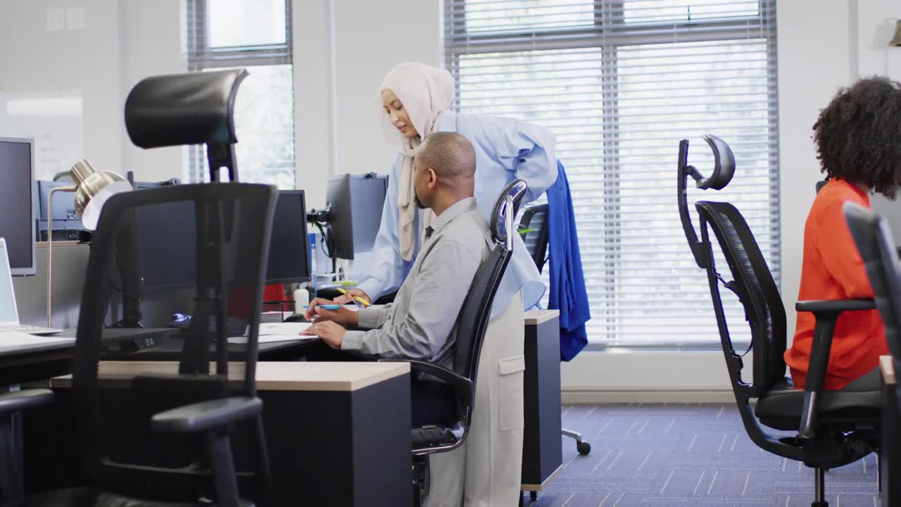 컴퓨터를 사용하고 사무실에서 이야기하는 다양한 사업가들의 그룹, 느린 동작