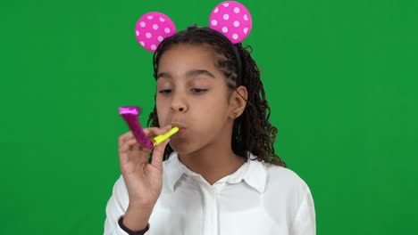 excited happy cheerful african american teen girl wearing mouse toy ears blowing party whistle smiling on green screen. portrait of joyful teenager celebrating birthday at chromakey background.