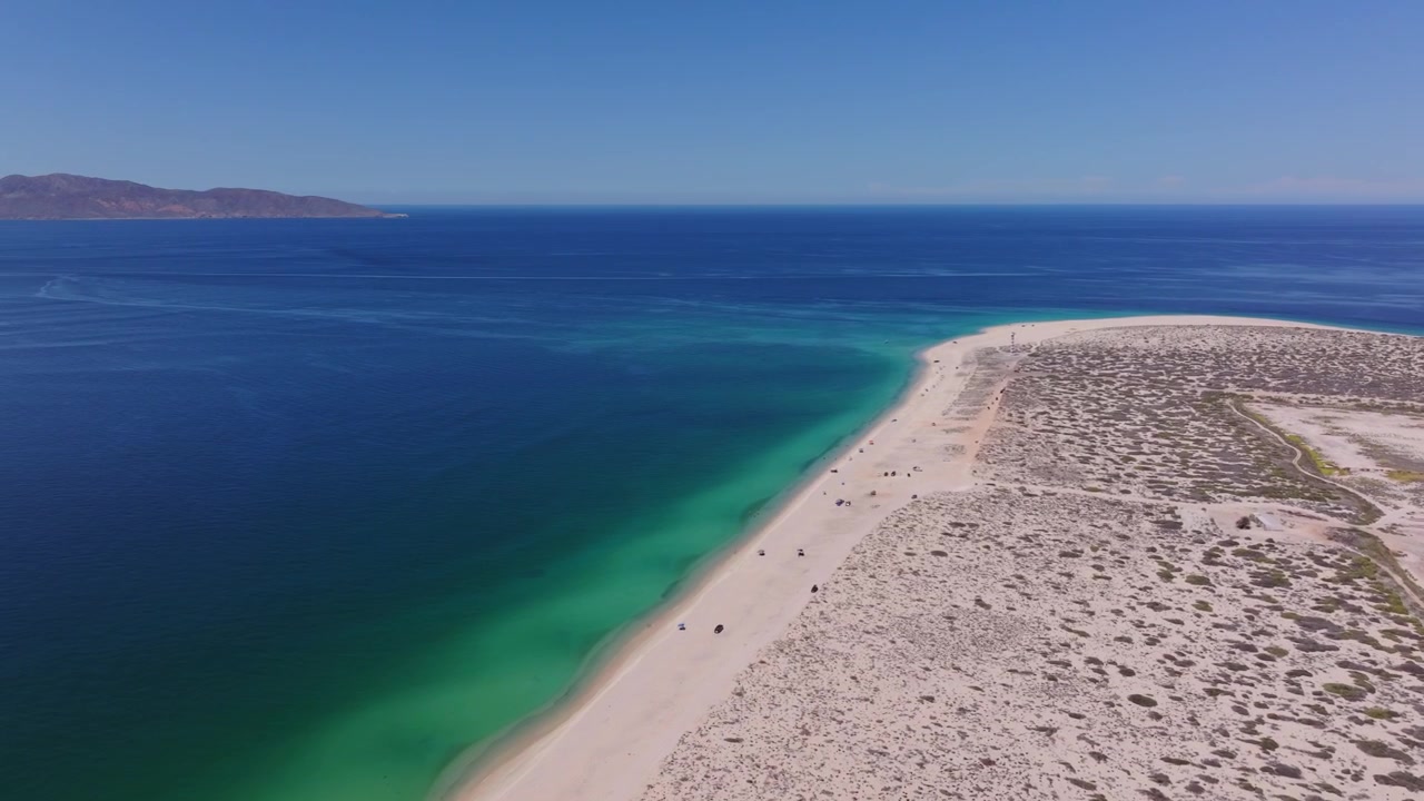 Perspectiva aérea de dron de ángulo alto mostrando el largo tramo de la playa Punta Arena en La Ventana, con la impresionante silueta de Isla Cerralvo en la distancia