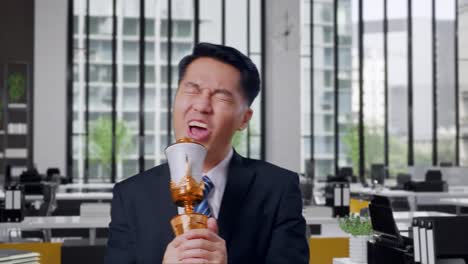 close up of asian business man in a suit and tie with a gold medal singing on a gold trophy celebrating winning as the first winner in office
