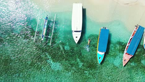 Antenne,-Touristen-Schnorcheln-Zwischen-Den-Fischerbooten,-Die-Im-Kristallklaren-Meerwasser-In-Der-Nähe-Des-Tropischen-Sandstrandes-Schwimmen