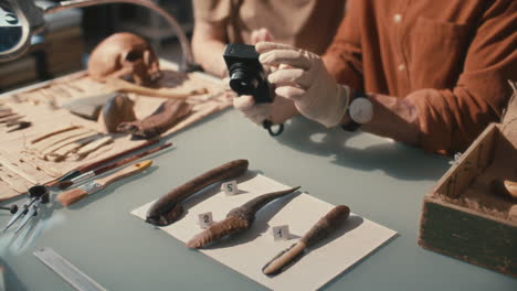 hands of archaeologists photographing ancient artifacts with camera