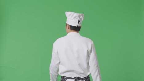 back view of asian man chef walking and looking around in the green screen background studio