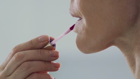 Nahaufnahme-Auf-Den-Lippen,-Seitenansicht-Einer-Frau,-Die-Drinnen-In-Zeitlupe-Lippenstift-Aufträgt