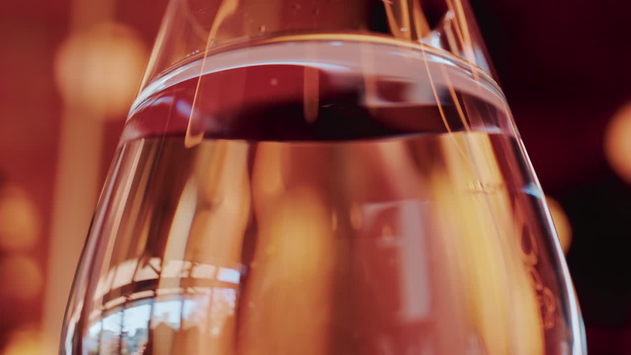 Close up of a transparent glass with warm ambient reflections in a cozy indoor setting