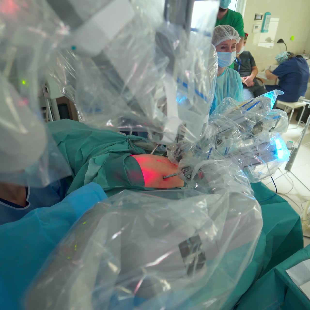 Da Vinci robot conducting abdominal operation. Robotic armed coated in plastic moving slowly over the patient on surgery table