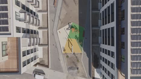 colourful playground in newly built apartments with solar photovoltaic panels on the roof. modern living concept. real estate building from above. aerial top down view. (4k)