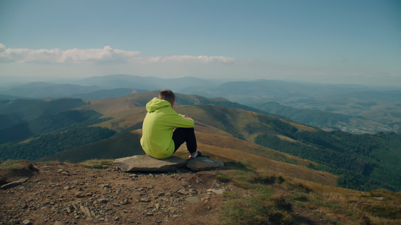 Young Guy Sitting on Stone and Watching on Landscape Young Guy Sitting on Stone Watching on Beautiful Landscape Feeling Breath of Warm Wind Frees Thoughts and Relaxing Spending Leisure Time Outdoor Face Closeup View