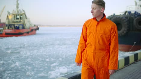 Dockarbeiter-In-Orangefarbener-Uniform-Mit-Blick-Auf-Das-Meer-Und-Im-Winter-Im-Hafen-Spazieren.-Vereistes-Meer