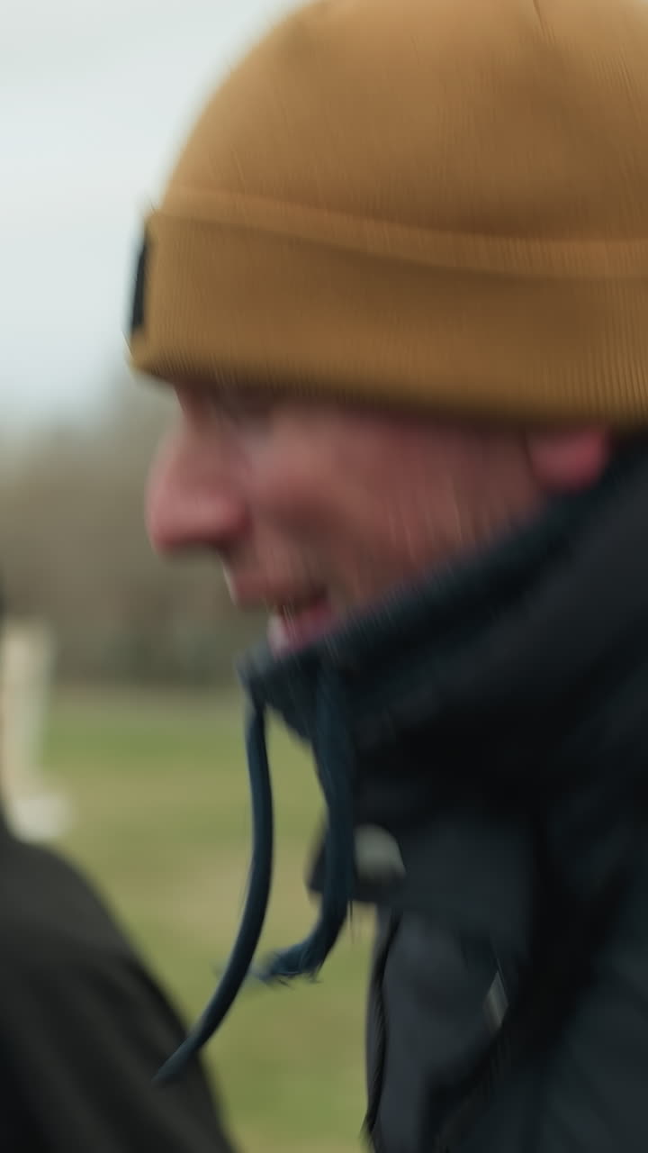 Close-up of three people jogging on a track near a grassy field, the coach appears to be discussing something with them, with a football post visible in the background