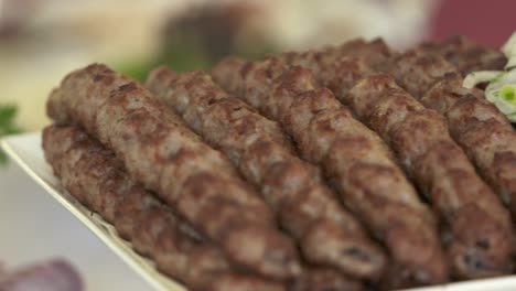 lula kebab armenio servido en una bandeja decorativa con cebolla picada
