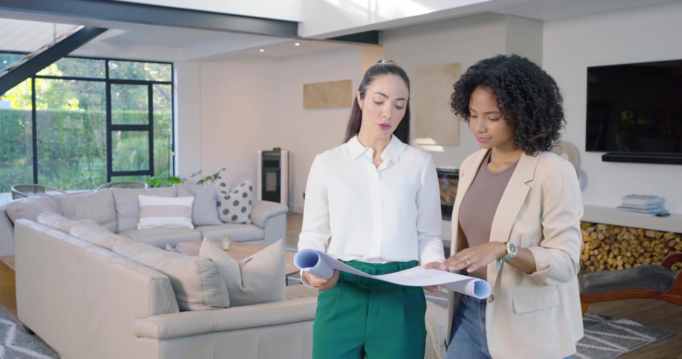 Diverse women entering living room, walking, scanning window and beam, unrolling plans for design