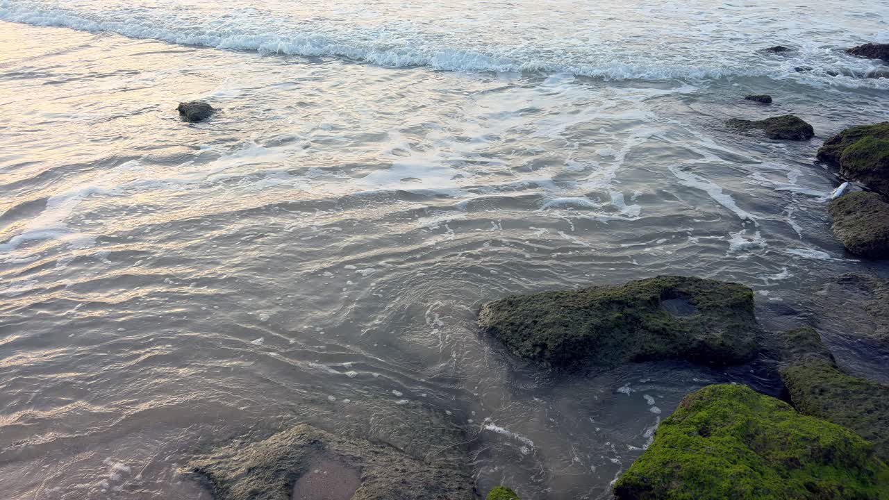 graciosas cascadas de agua de mar sobre las rocas de la playa de arena en tranquila armonía costera