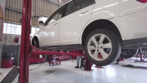 lowering of a white car on a red car lift at a workshop station garage at mexico latin-america