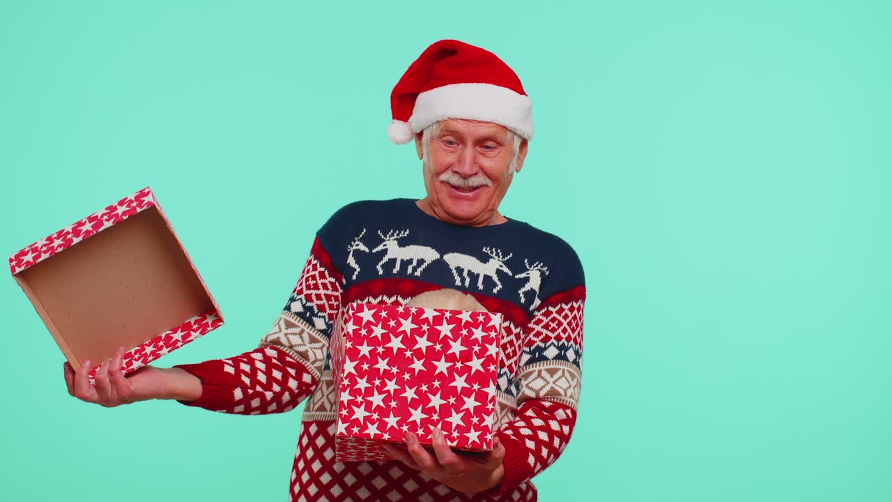 Grandfather in christmas sweater smiling unwrapping gift opening box with pet cat great surprise