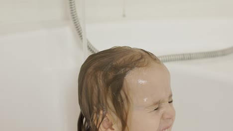 attractive three years old girl takes a bath. cleaning and washing hair