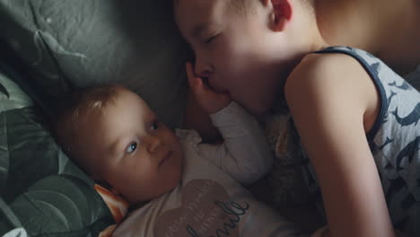 brother playing with baby sister while in bed