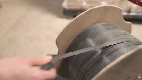 a close-up of a worker taking plastic wrapping rope from a spool to pack the briquettes