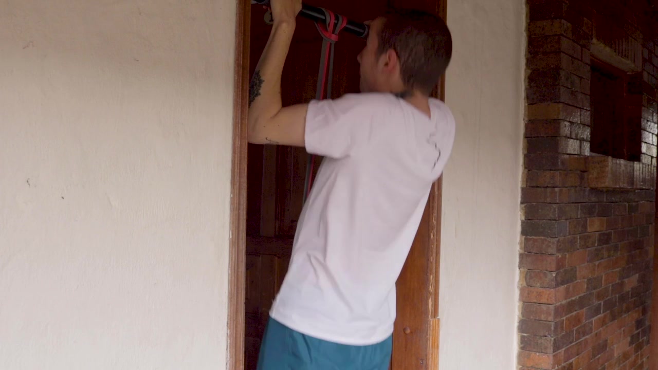 Young man doing assisted pull ups at home, side shot.