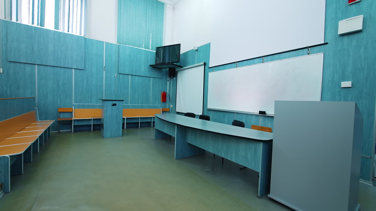 Modern interior of lecture hall. White board and presidium table in the university classroom. Empty auditorium with new equipment.