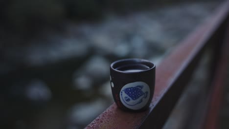 river in japanese mountain, focus reveal of hot sake on rail