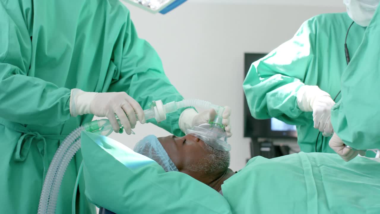 Diverse surgeons giving anesthesia to patient in operating theatre, slow motion
