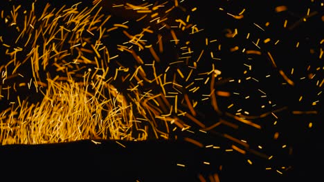burning red hot sparks rise from fire in the night sky