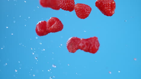 explosion on fresh raspberries with water, flying in air after launch