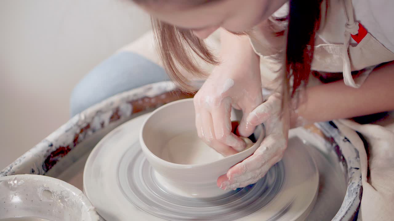 mujer formando un cuenco en una rueda de cerámica