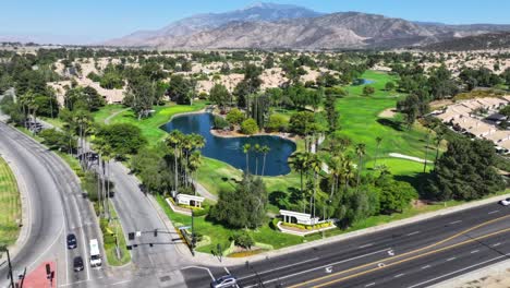 fast-hyperlapse-over-a-busy-intersection-leading-up-to-a-luxurious-golf-course-with-a-large-pond-and-fountain-AERIAL-DOLLY