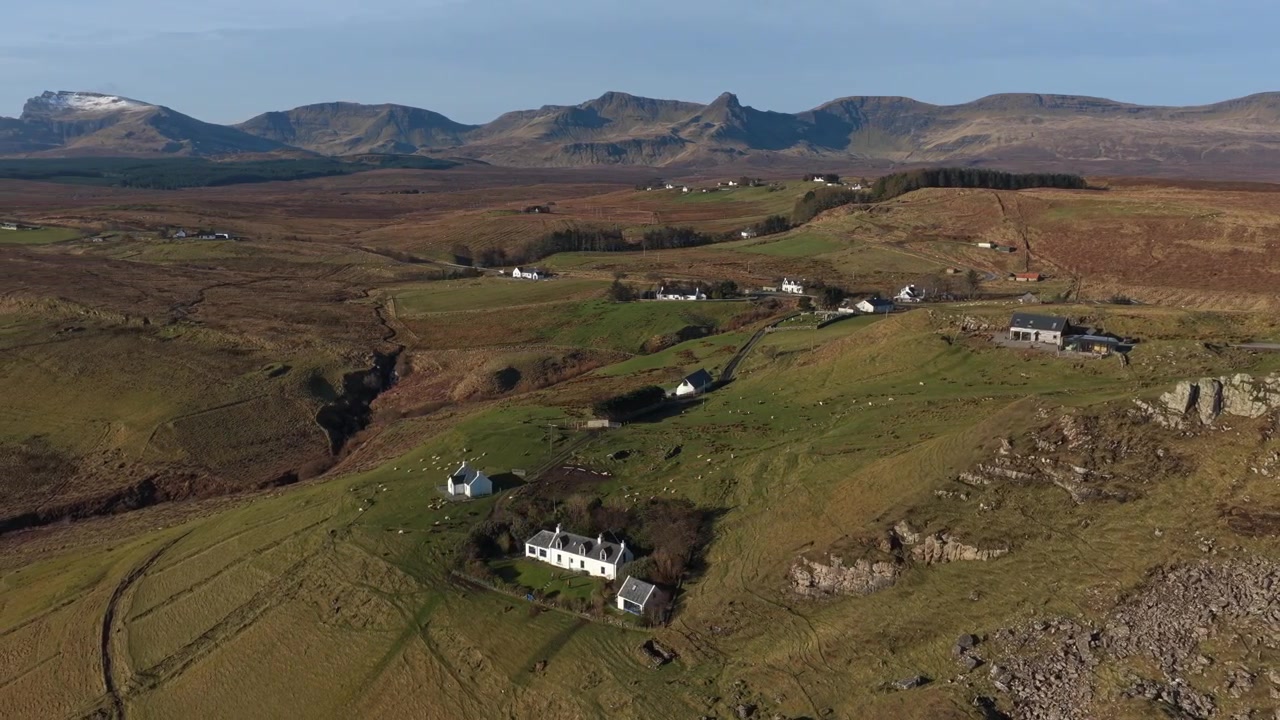 Ampie riprese aeree che mostrano lo splendido paesaggio rurale di Brothers Point sull'Isola di Skye, con case sparse e montagne.
