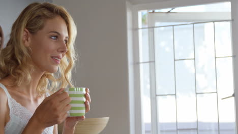 una rubia linda tomando café en la cocina.