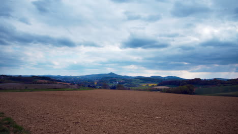 panorama panning - pan shot of the oelberg (ölberg siebengebirge) in germany near bonn with dramatic clouds, nice landscape and a plowed field in the foreground