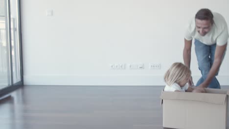 Happy-dad-dragging-box-with-little-daughter-inside