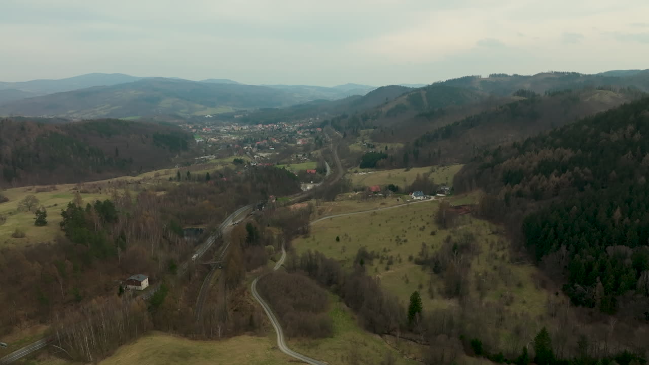 una vista aérea panorámica de jedlina-zdrój, que muestra la posición de la ciudad enclavada dentro de un verde valle flanqueado por colinas boscosas onduladas