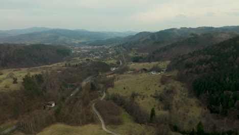 Eine-Malerische-Luftaufnahme-Von-Jedlina-Zdrój,-Die-Die-Eingebettete-Lage-Der-Stadt-In-Einem-Grünen-Tal-Zeigt,-Das-Von-Sanften,-Bewaldeten-Hügeln-Flankiert-Wird.