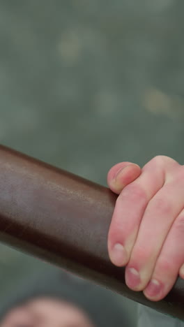 close-up of a young boy gripping an iron bar during a workout session, with a blurred view of the boy s face and surroundings