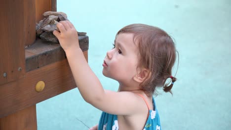 Gesicht-Nahaufnahme-Eines-Schönen-Kleinkindmädchens,-Das-Steine-Auf-Dem-Spielplatz-Stapelt---Zeitlupe