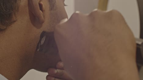 close up of man using trimmer to shave his face